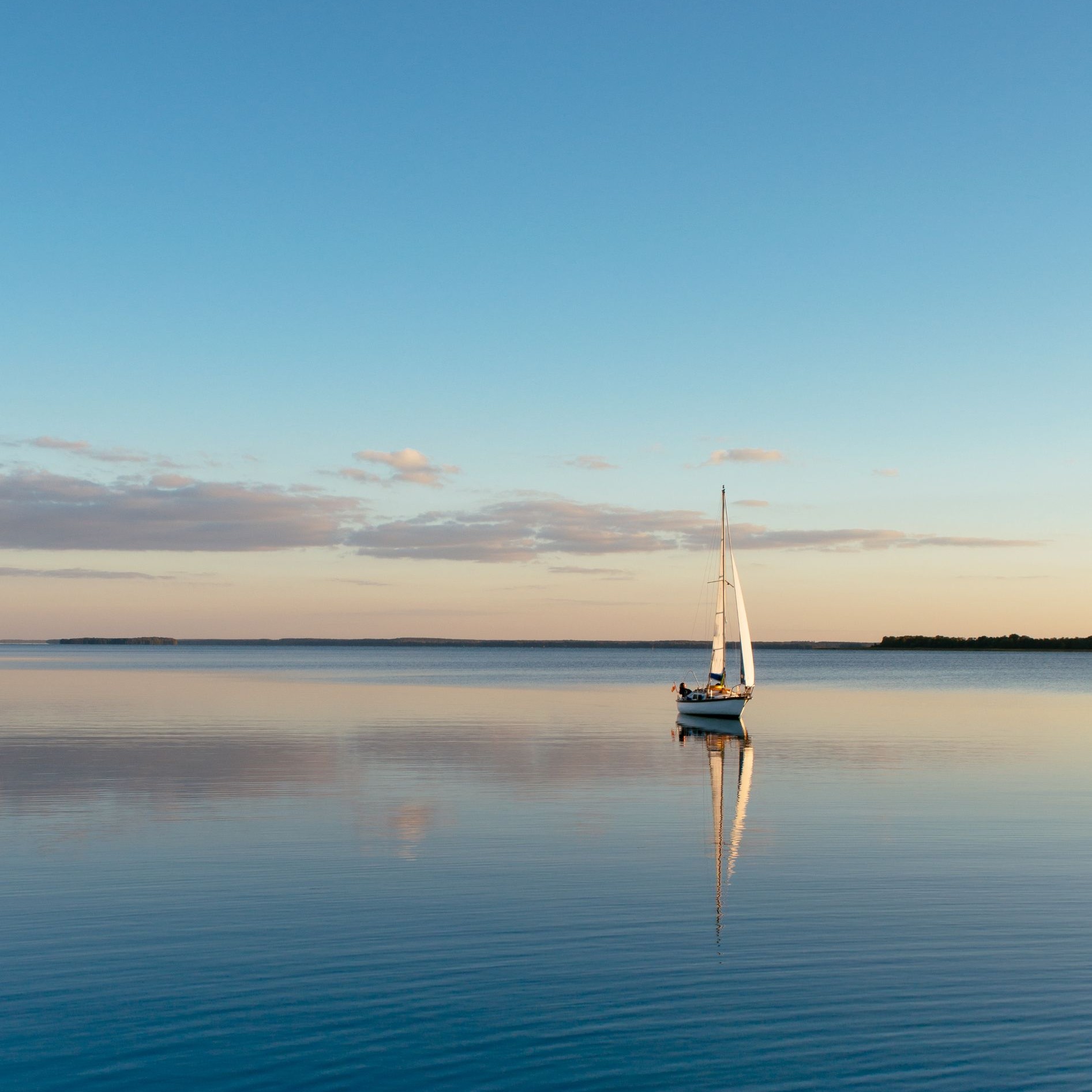 Sailing boat on a calm lake with reflection